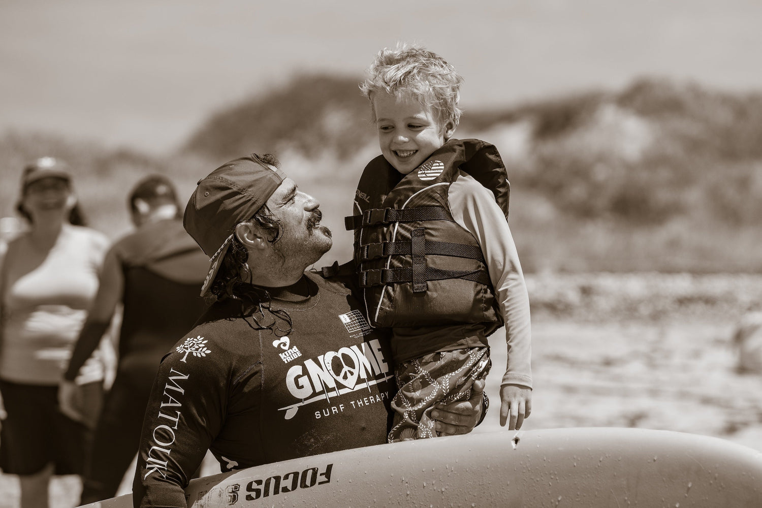 Gnome Surf® surf gear collection including rashguards, wetsuits, surfboards, wax, leashes, and accessories, fueling surf therapy programs for children.